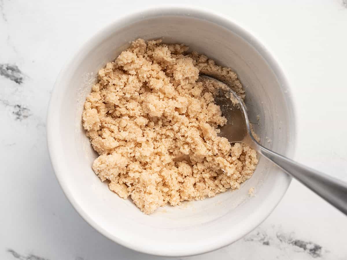 Crumble topping mixture in a small bowl with a spoon.