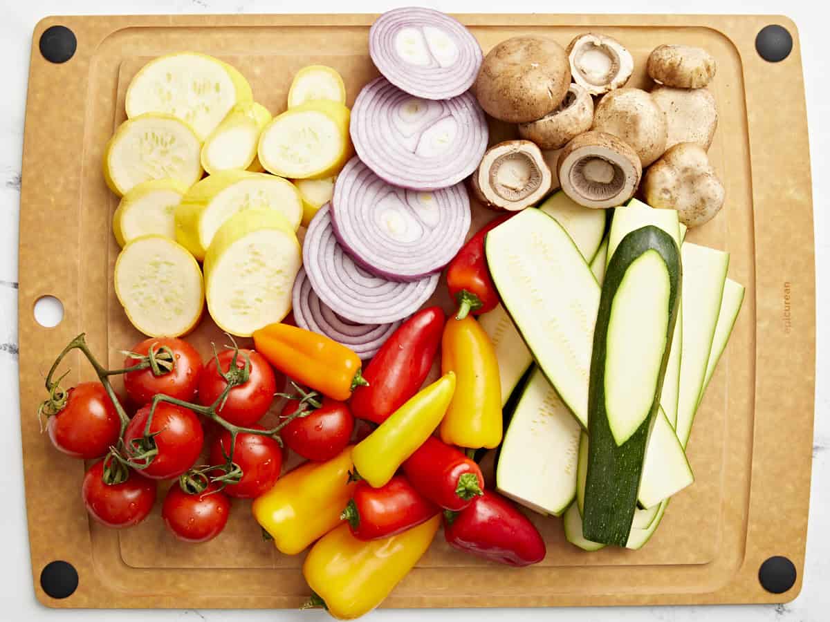 Overhead view of chopped vegetables on a wooden chopping board.