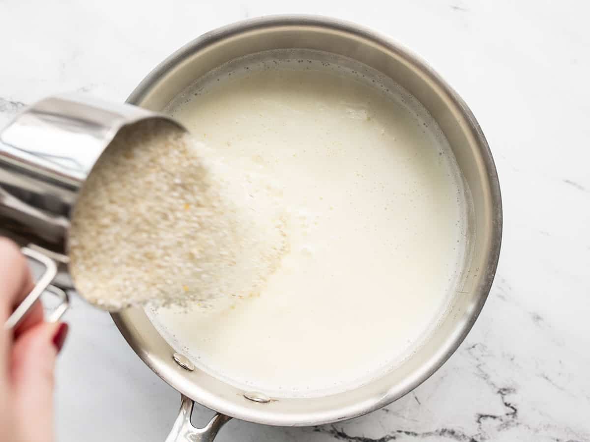 grits being poured into the pot with the milk and broth