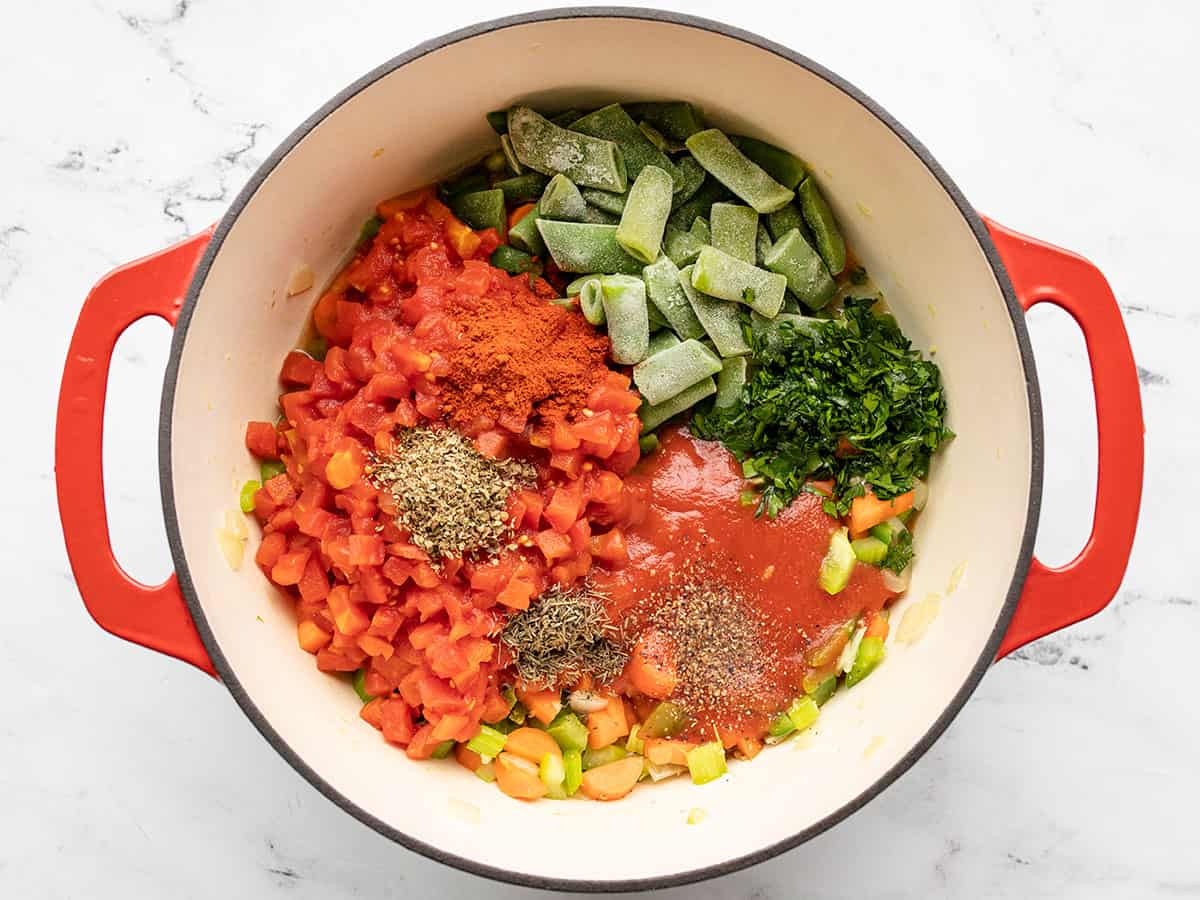 Tomatoes, spices, parsley, and green beans added to the pot