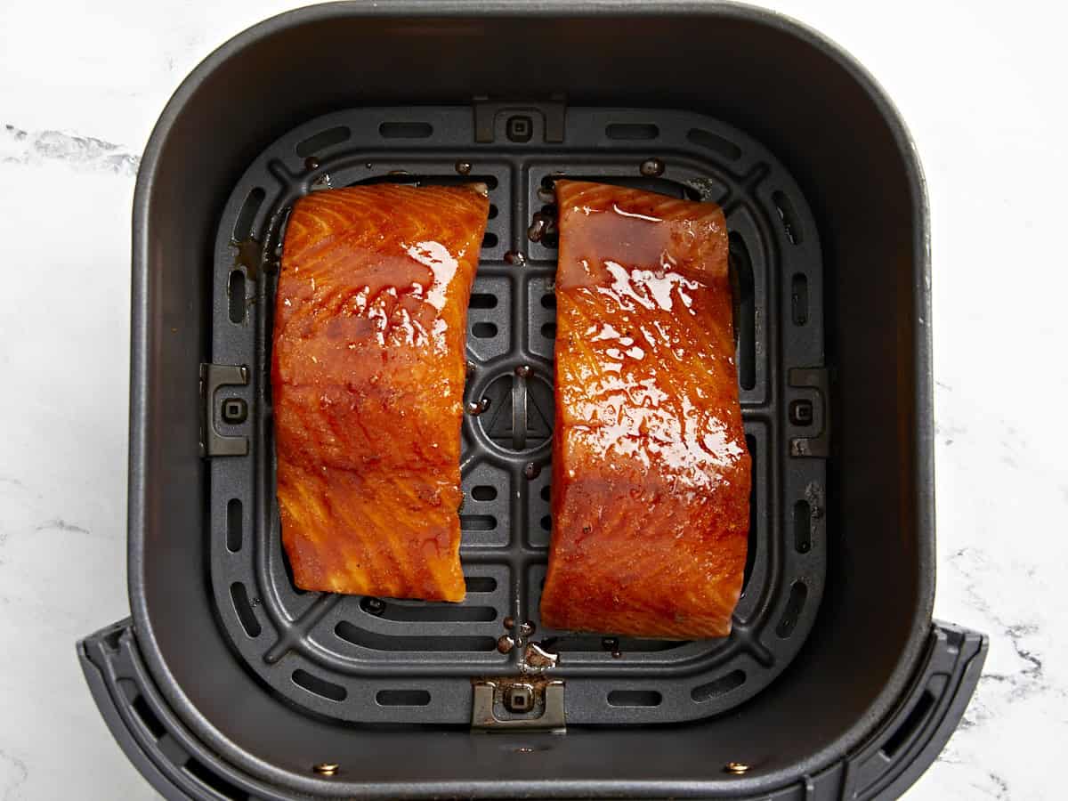 marinated salmon filets in an air fryer basket.