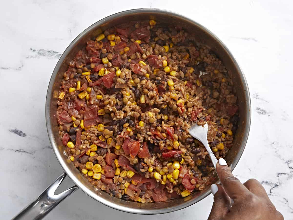 Cooked southwest lentils and rice skillet with rice being fluffed with a fork.