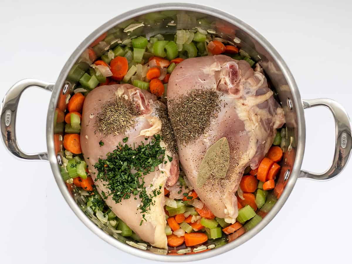 Chicken and herbs added to the soup pot.