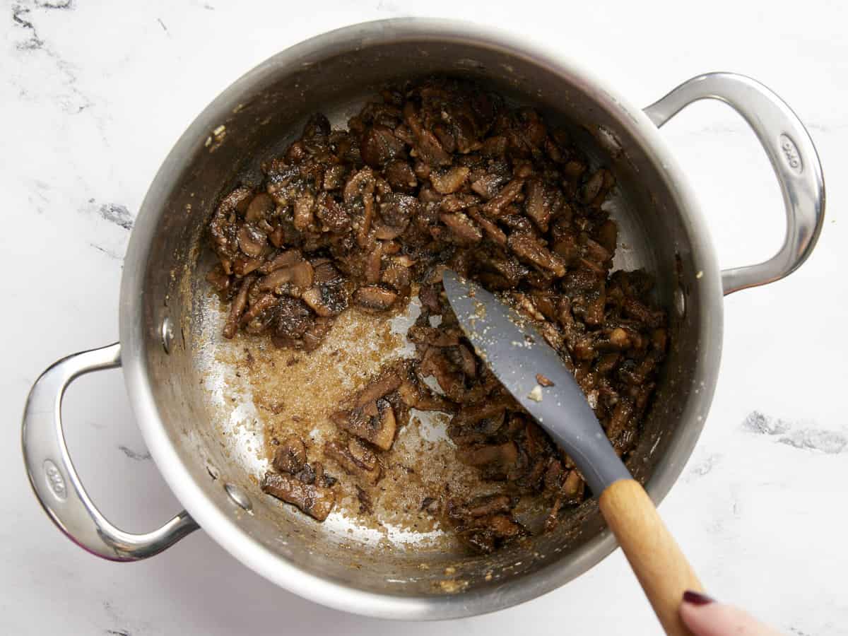 Browned roux showing on the bottom of the pot under the mushrooms. 