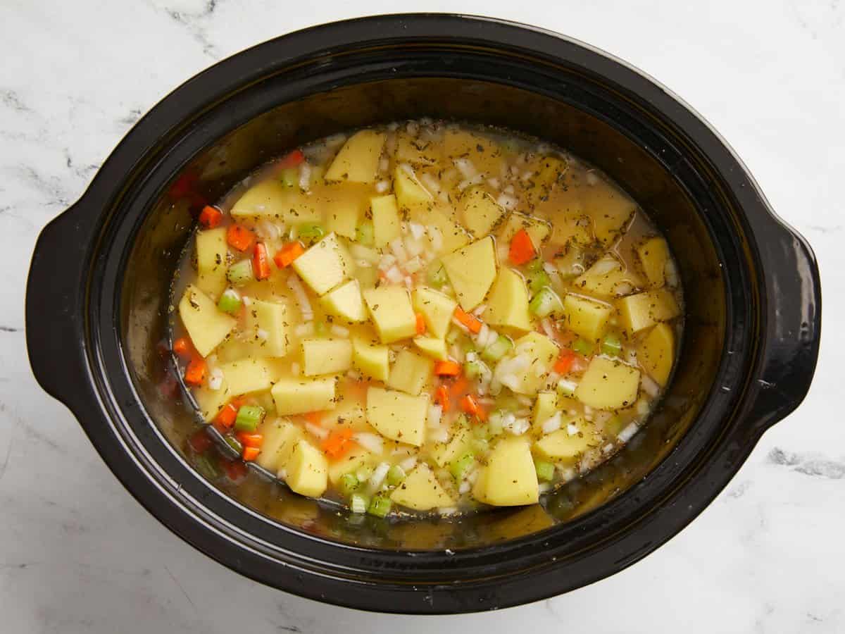 Potato soup ingredients added to a slow cooker and mixed.