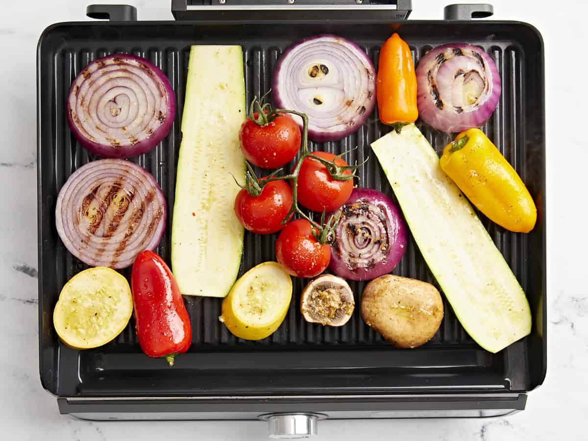 Overhead view of sliced vegetables on a grill.