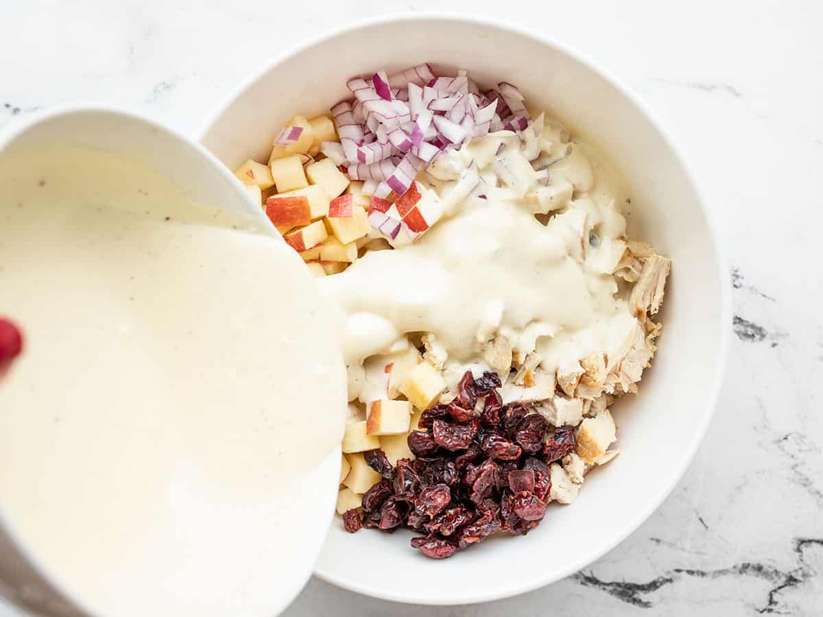 Dressing being poured over the chicken salad ingredients