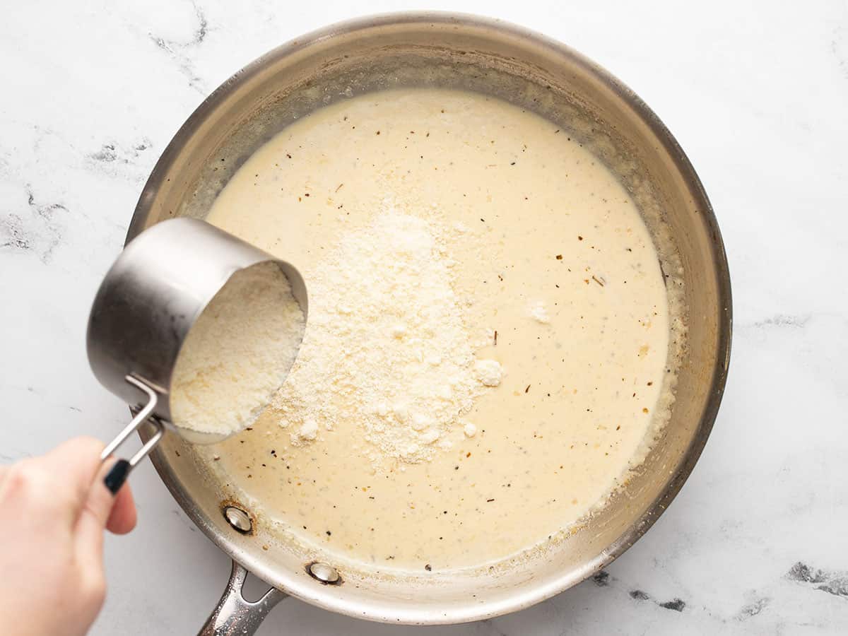 Parmesan being added to the skillet.