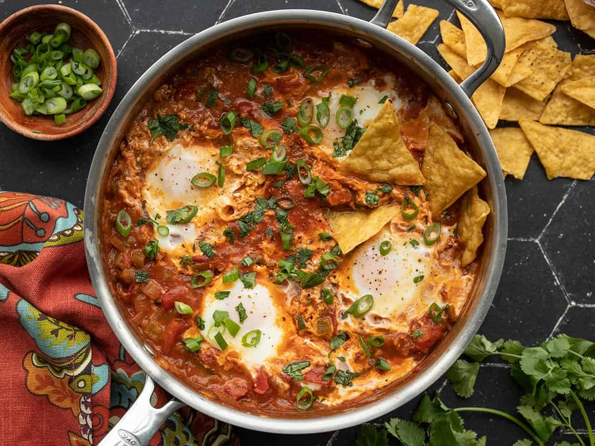 Finished salsa poached eggs with chips and green onion on the sides