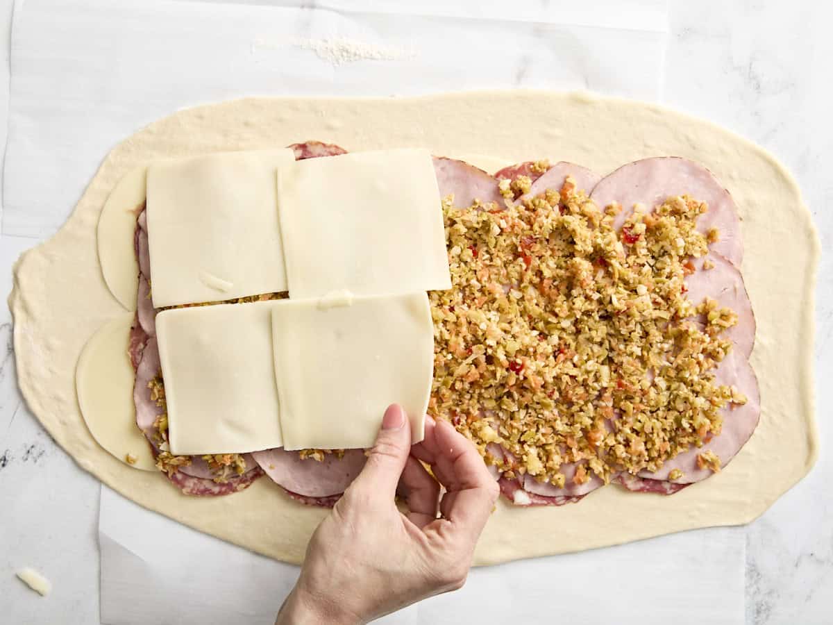 Adding last cheese layer to a muffaletta roll up