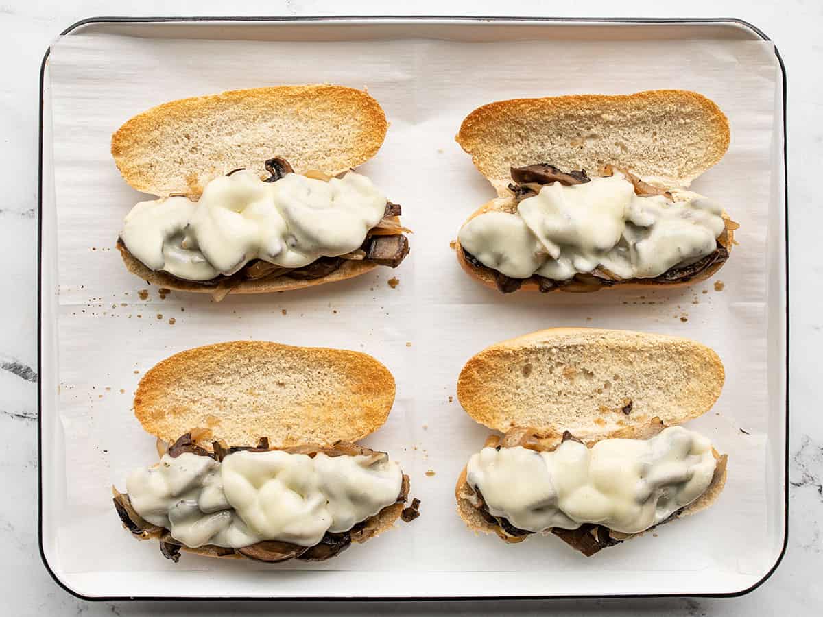 Melted cheese on the sandwiches on the baking sheet.