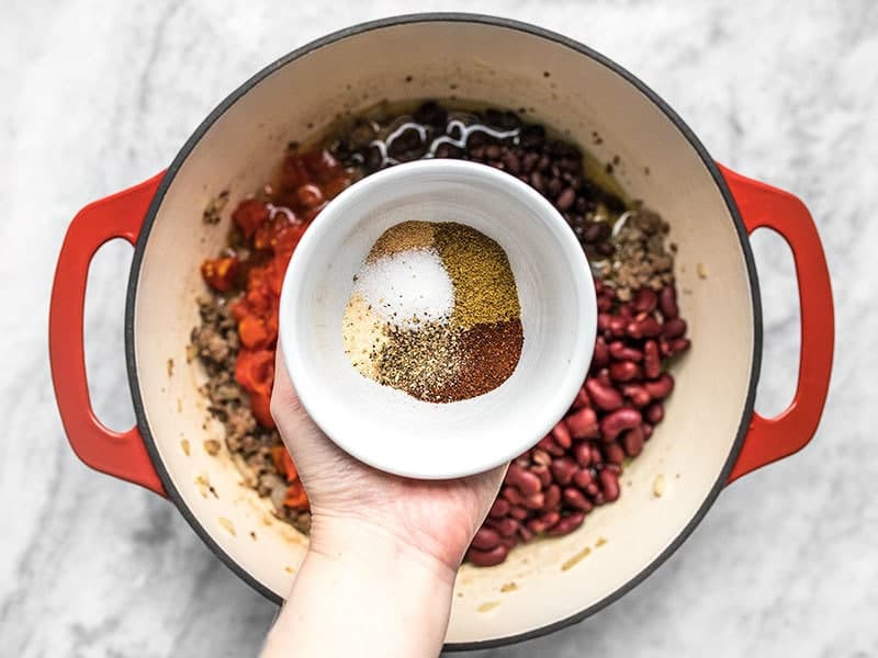 Add spices to the pot with beef, beans, and tomatoes