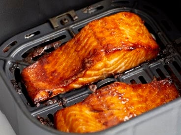 close up of air fryer salmon filets in an air fryer basket.