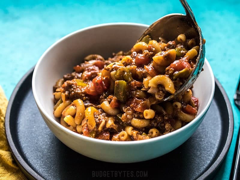 One Pot American Goulash being ladled into a bowl.