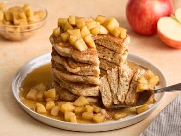 Front view of a stack of apple cinnamon pancakes with fork lifting some out.