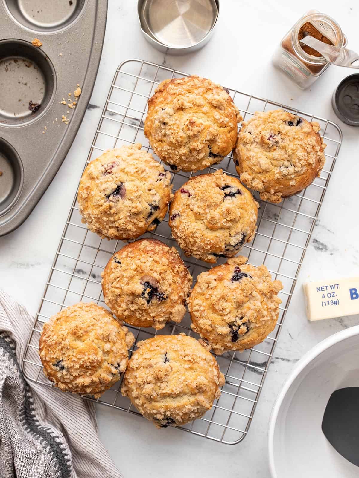 Baked blueberry muffins on a wire rack surrounded by baking supplies.