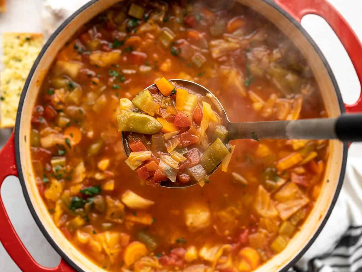 A ladle full of cabbage soup held over the pot