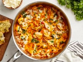 Overhead view of cheese tortellini and sausage skillet with garlic bread and parsley on the side.