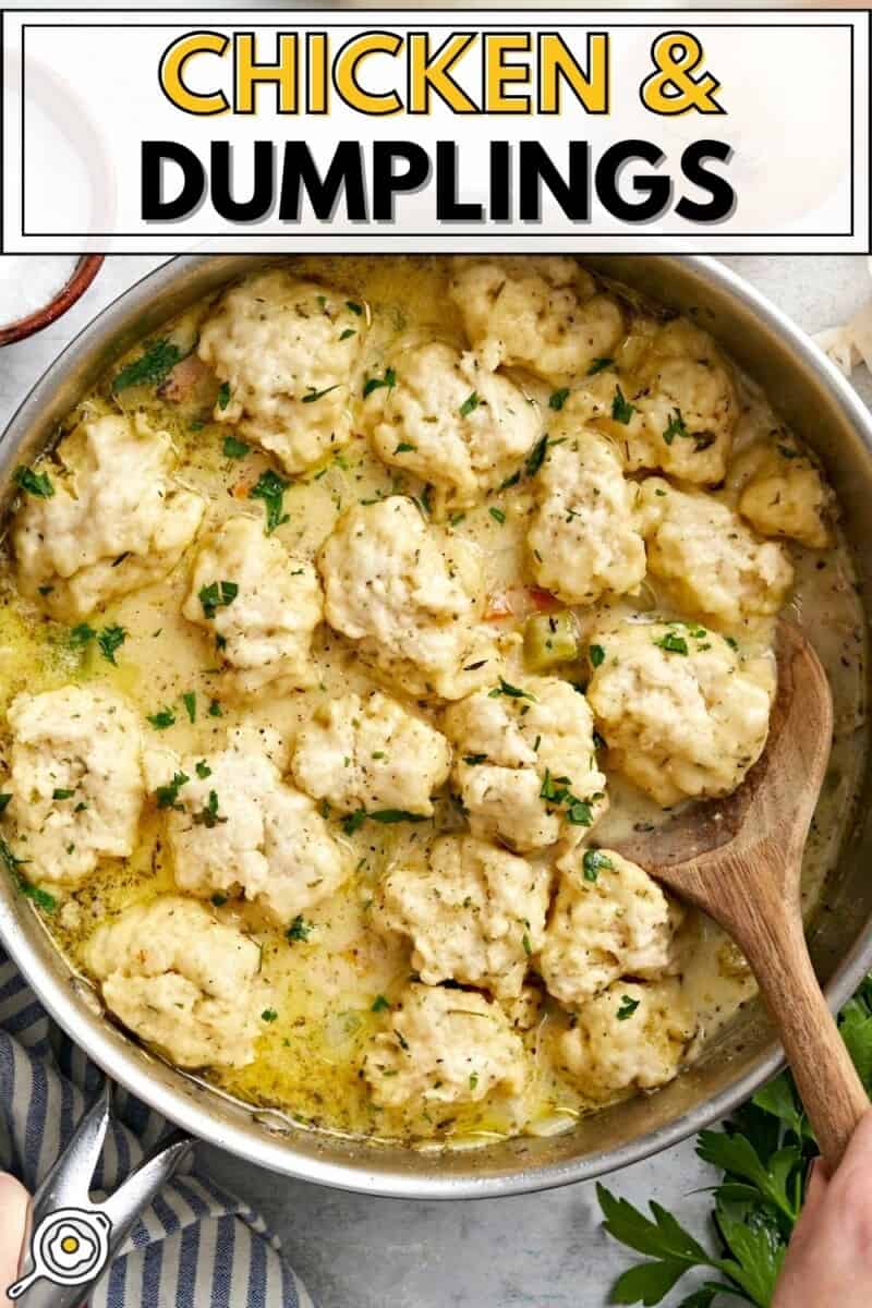 Overhead view of a skillet full of chicken and dumplings with a wooden spoon.