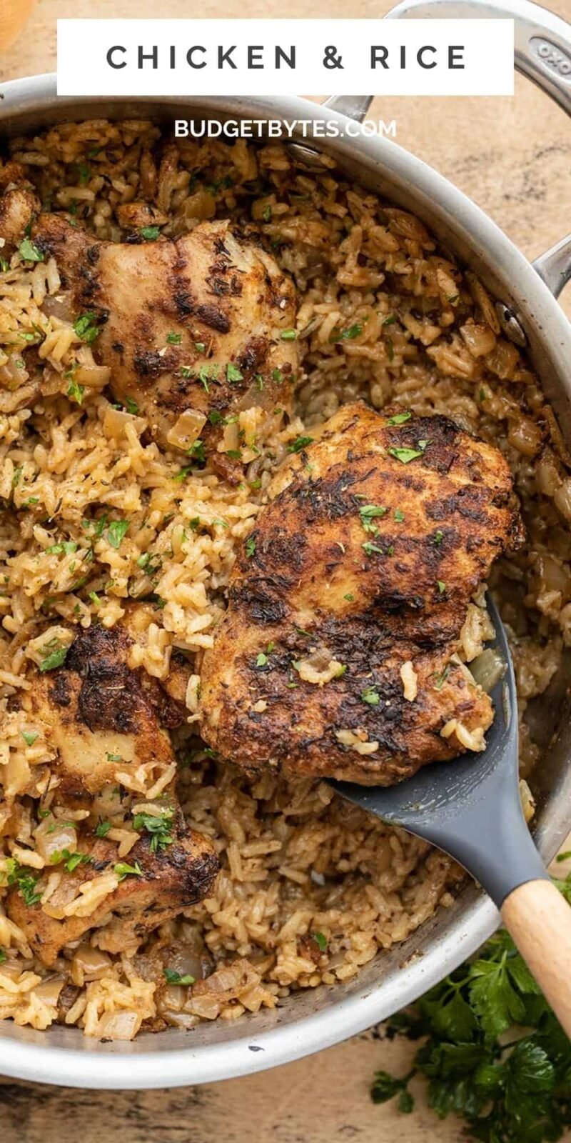 Overhead view of chicken and rice being scooped out of the skillet.