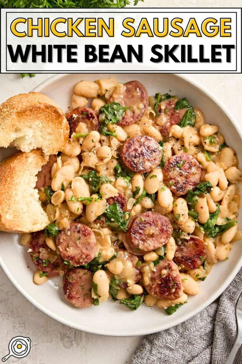 Overhead view of chicken sausage and white beans on a serving dish with toasted bread on the side and title text at the top.