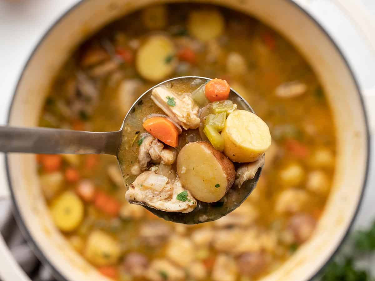 A ladle full of chicken stew held over the pot