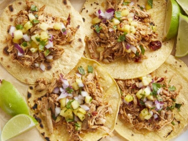 Close up overhead view of chipotle chicken tacos with limes on the side.