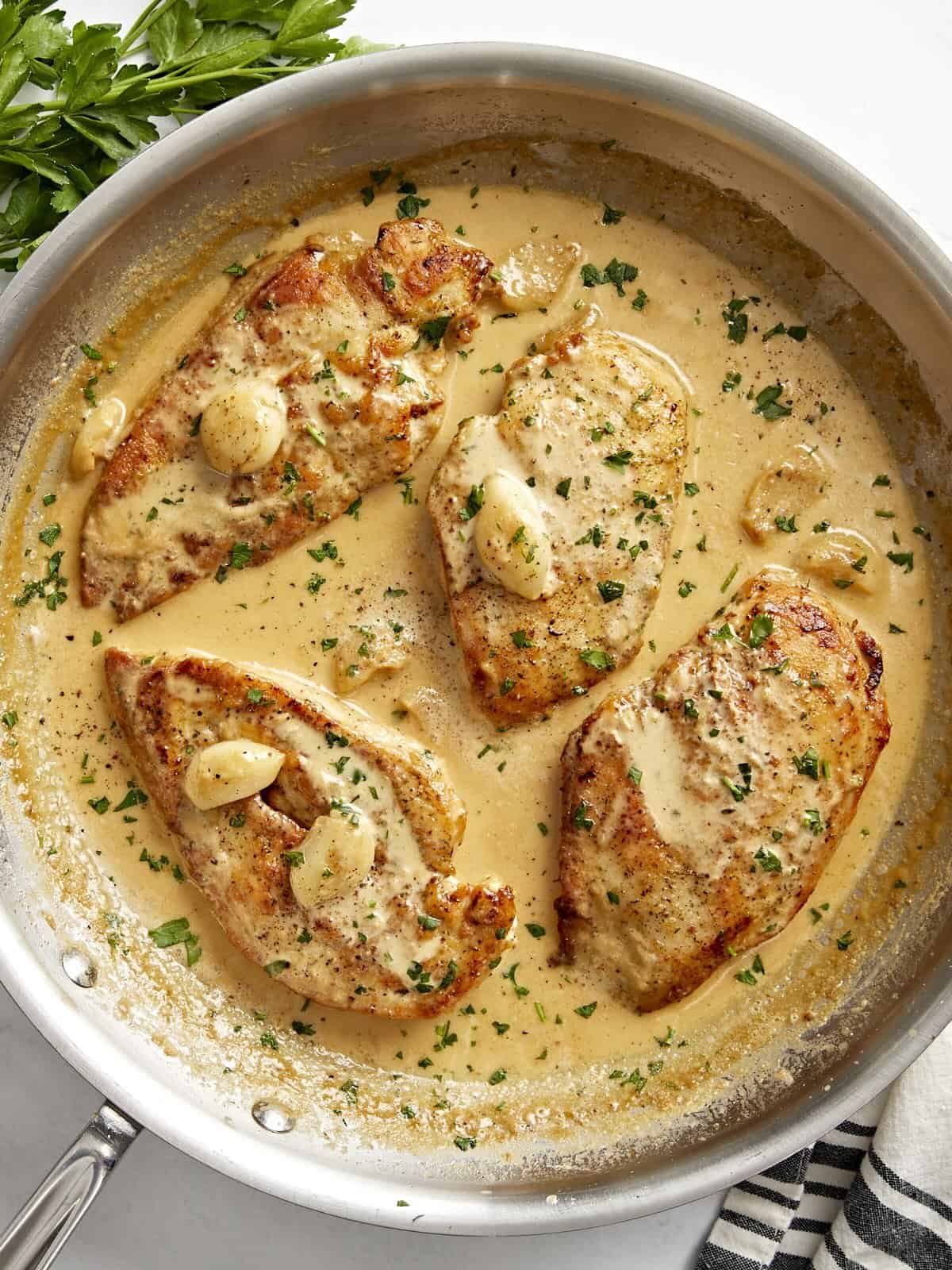 Overhead view of Creamy Garlic Chicken in a skillet with parsley garnished on top.