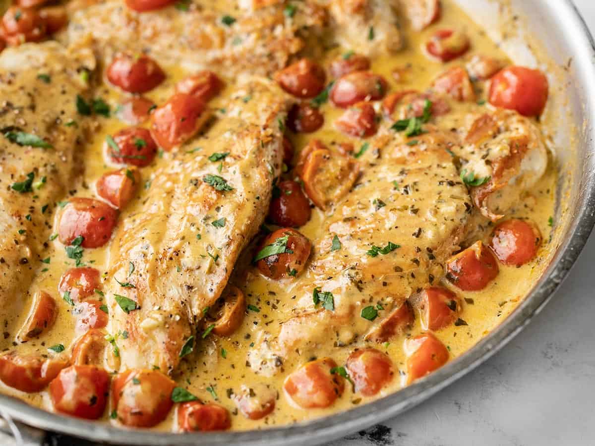 Side view of creamy pesto chicken in the skillet.