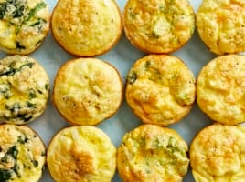 Cooked egg muffins lined up in a grid on a blue surface.