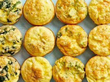 Cooked egg muffins lined up in a grid on a blue surface.