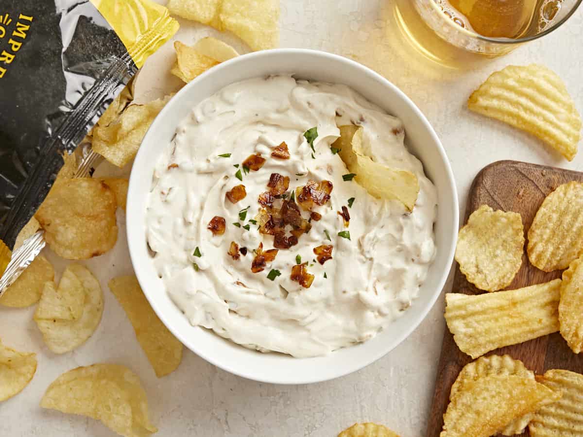 Overhead view of a bowl of French Onion Dip with a chip in the side and chips all around.