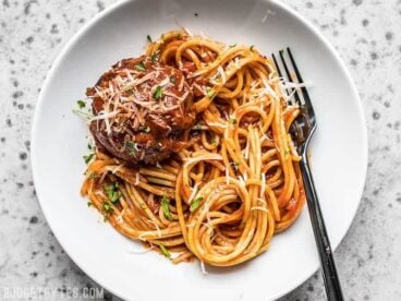 A plate with spaghetti, marinara, and a giant slow cooker meatball.