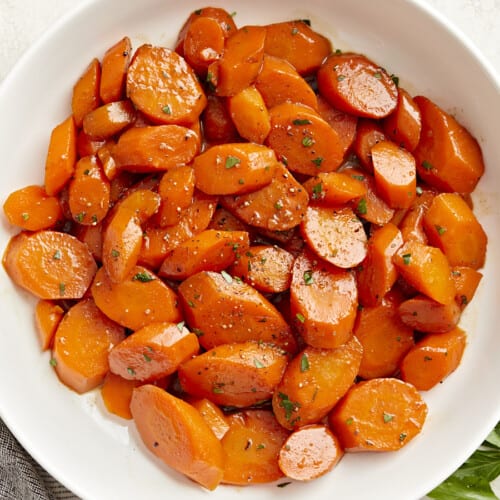 Overhead view of glazed carrots in a white serving dish.