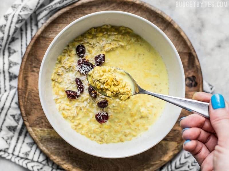 A spoonful of Golden Overnight Oats being lifted from the bowl. 