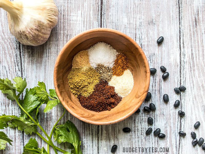 The spices needed for homemade chili seasoning in a wooden bowl before being stirred together. 