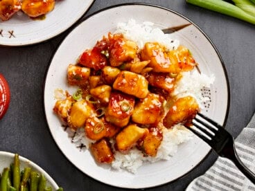 Overhead view of honey garlic chicken on a plate with white rice and a black fork.