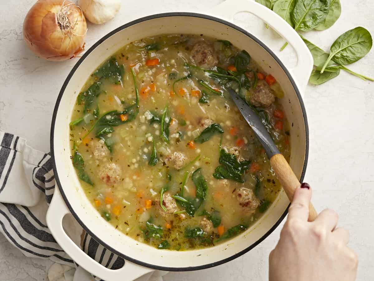 Overhead view of a pot of Italian Wedding Soup being stirred.