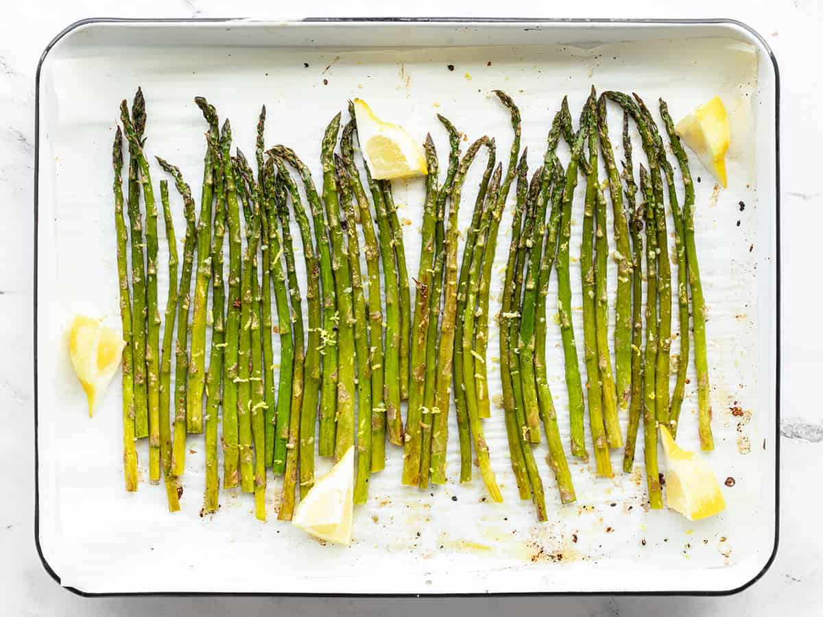 Lemon Garlic Rosted Asparagus on a sheet pan with lemon wedges