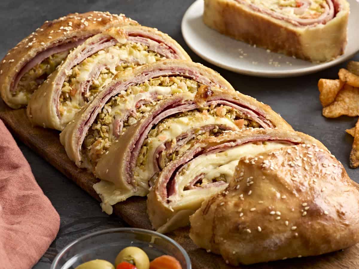 Muffaletta roll ups on a wooden chopping board