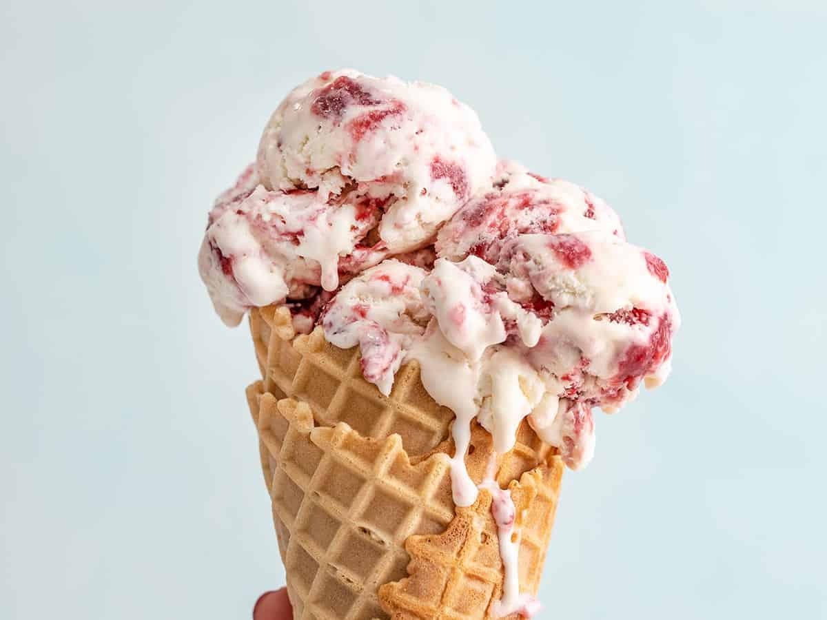 Close up side view of a strawberry ice cream cone.