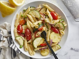 A bowl of pasta primavera with a fork in the center.