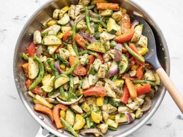 Easy pesto chicken and vegetables in a skillet with a spatula