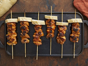 Overhead shot of Pinchos De Pollo on a black grill plate.