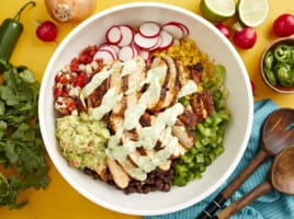 creamy avocado dressing drizzled over santa fe salad in a large white bowl.