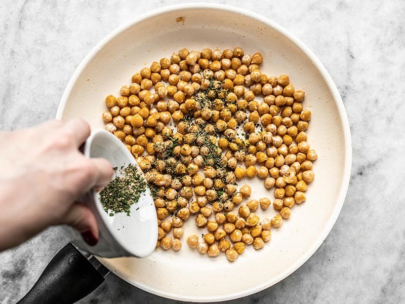 Season Chickpeas in skillet with garlic herb seasoning.