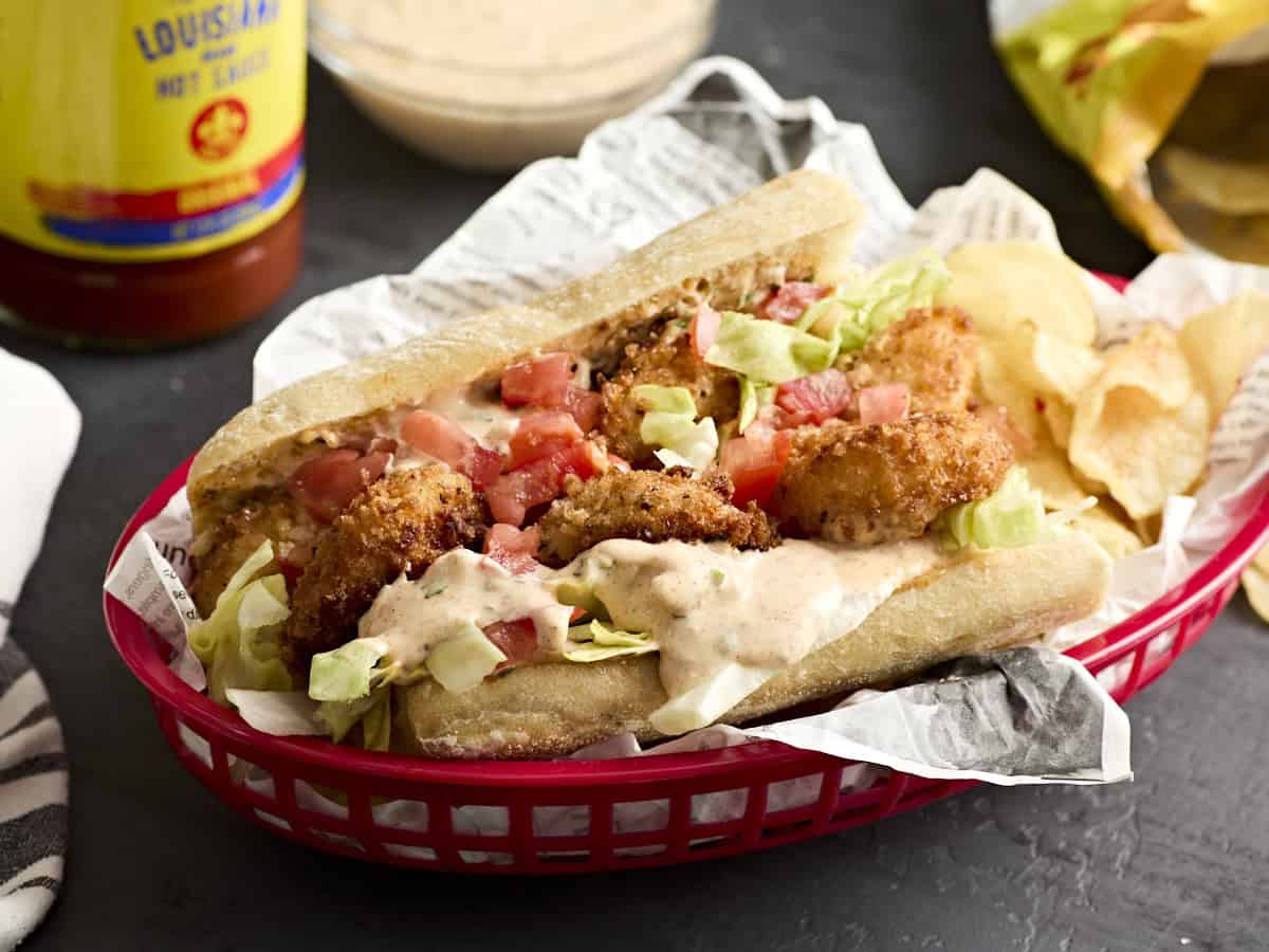 A shrimp po' boy with lettuce and tomato in a basket