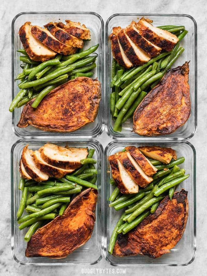 Four glass meal prep containers with Smoky Chicken and Cinnamon Roasted Sweet Potatoes