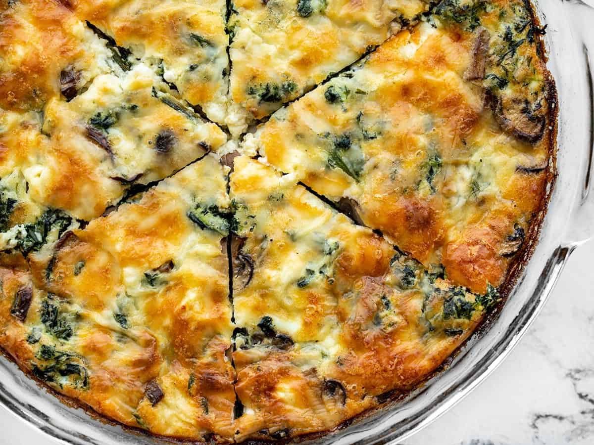 close up view of sliced spinach and mushroom crustless quiche in the pie dish