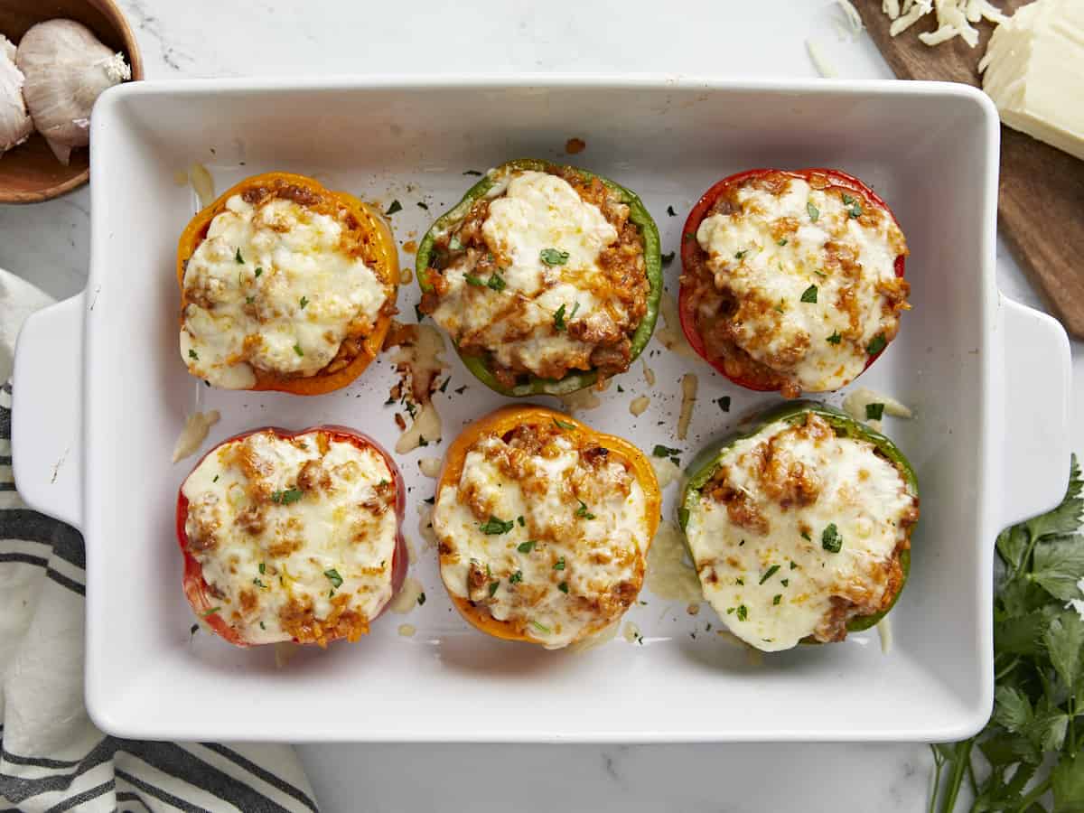 Overhead view of 6 stuffed bell peppers in a white casserole dish.